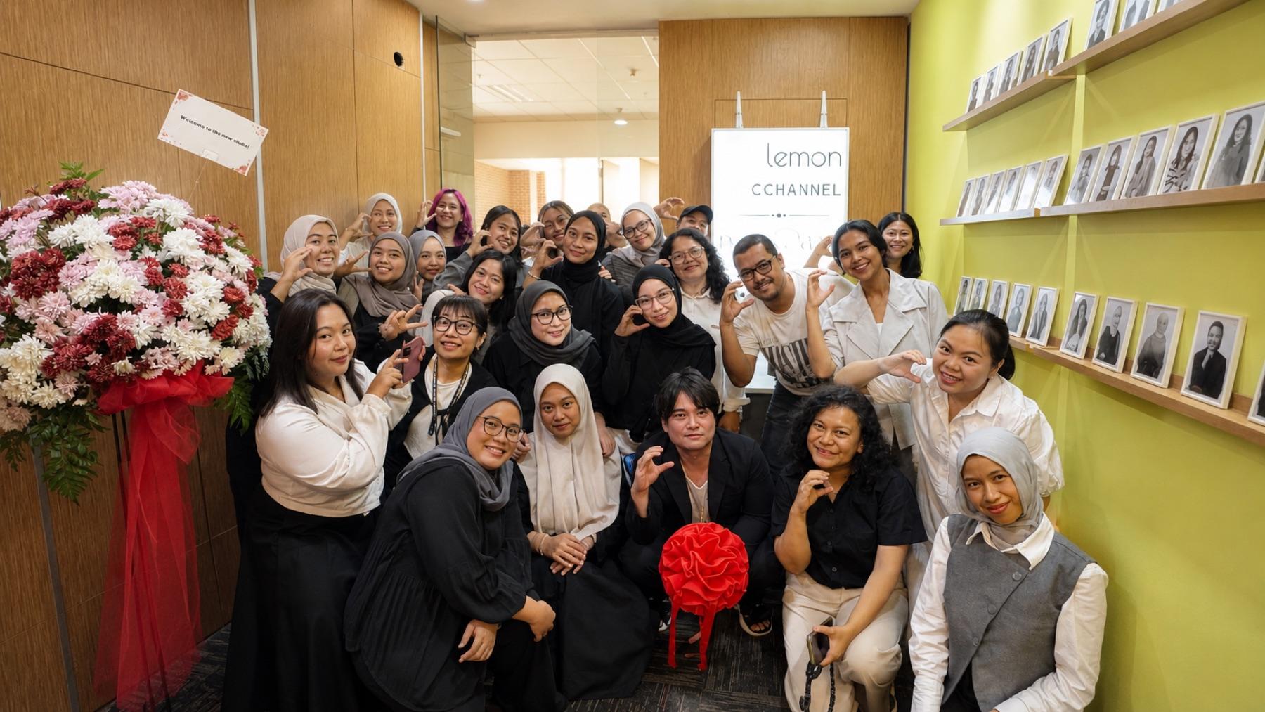 The C CHANNEL and lemon team gathered together in the new Mega Kuningan office on opening day, with a congratulatory flower stand by the door.